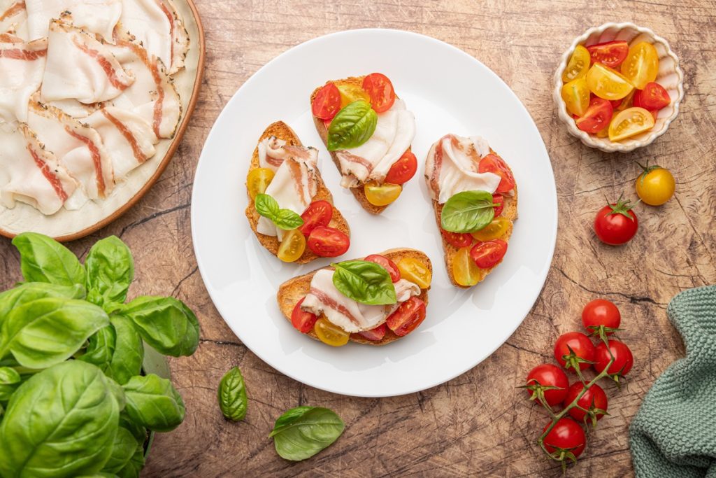 Bruschette con lardo, pomodorini gialli e rossi e basilico
